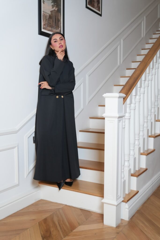 A woman in a long black dress standing on a staircase
